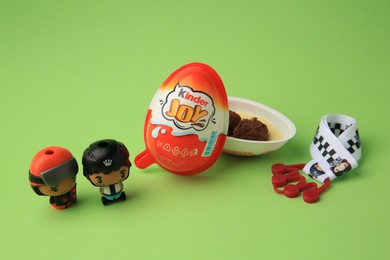 Photo of Sveti Vlas, Bulgaria - June 29, 2023: Halves of Kinder Joy Egg with sweet candies and toys on light green background
