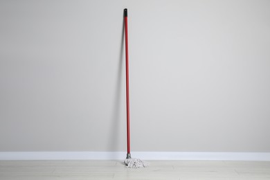 Photo of Mop with plastic handle near wall indoors