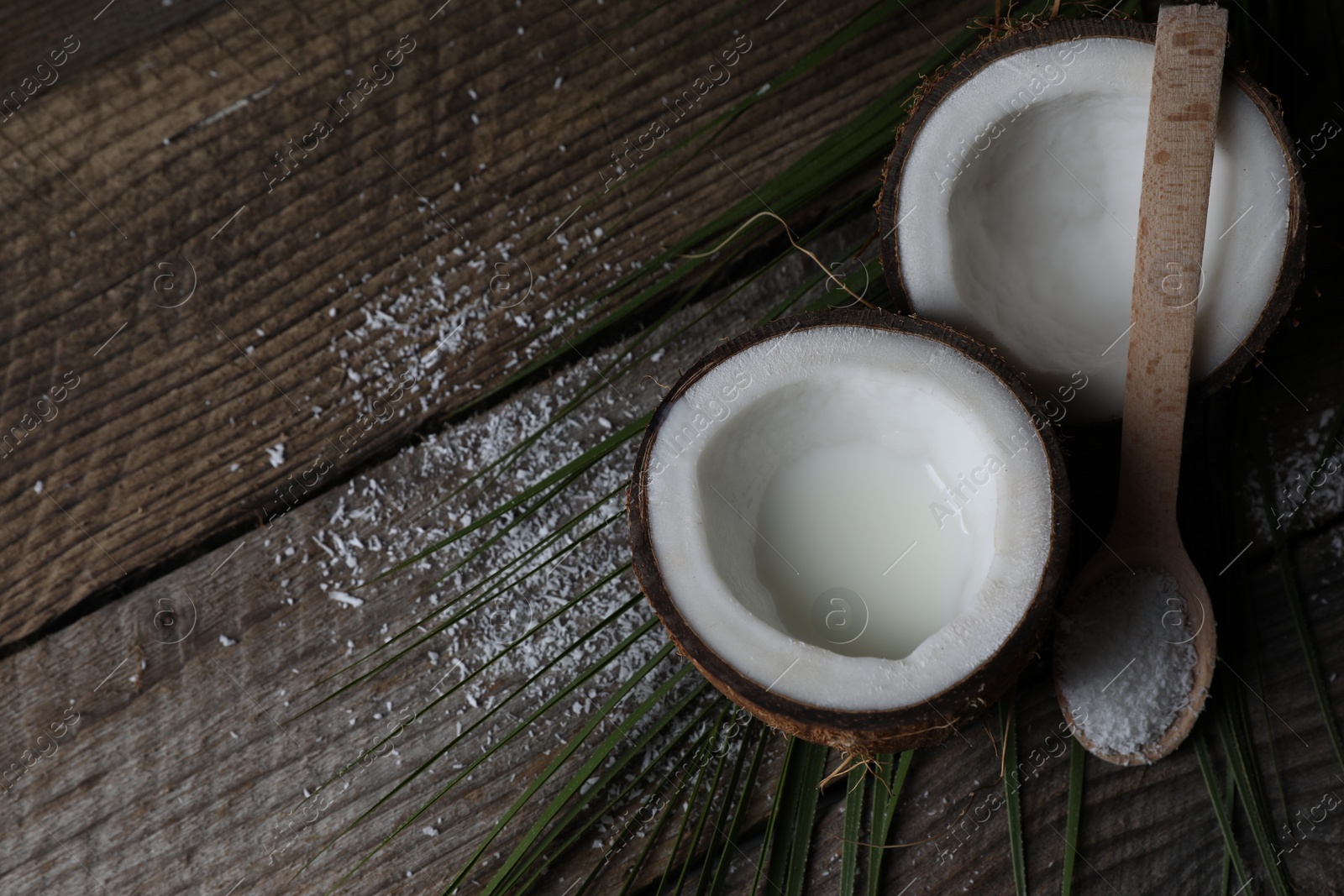 Photo of Coconut milk, flakes, nuts and palm leaf on wooden table, above view. Space for text