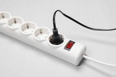 Photo of Power strip with electrical plug on white background, closeup