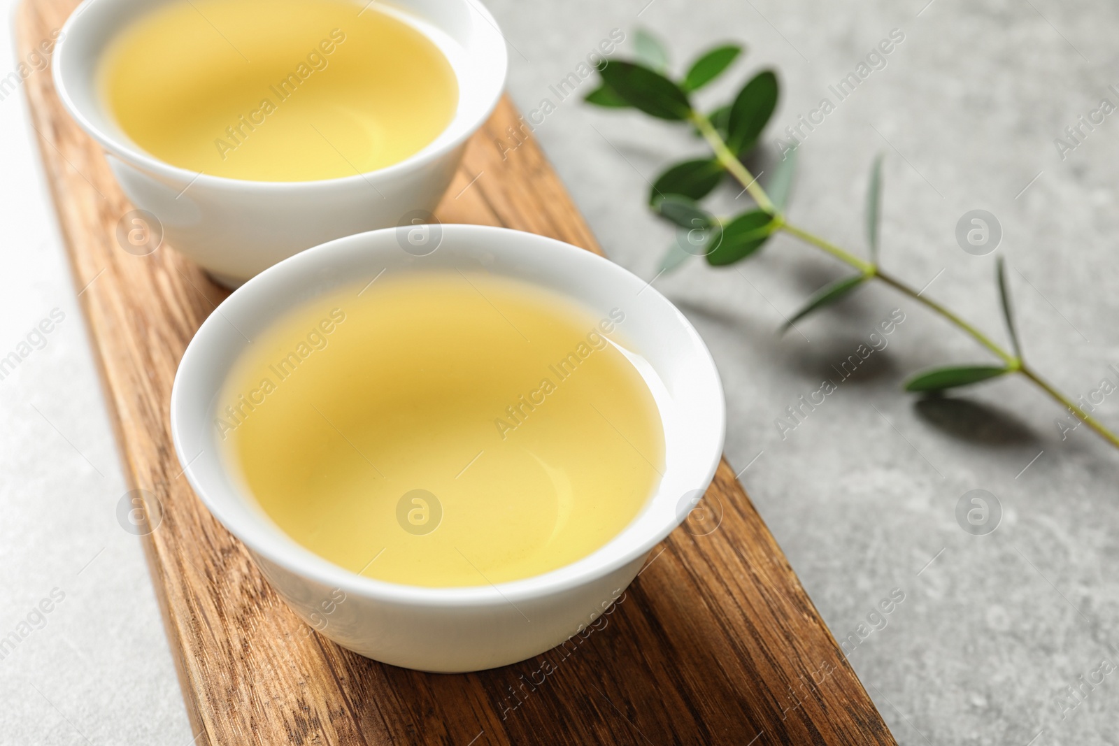 Photo of Stand with cups of freshly brewed oolong tea on grey table, space for text