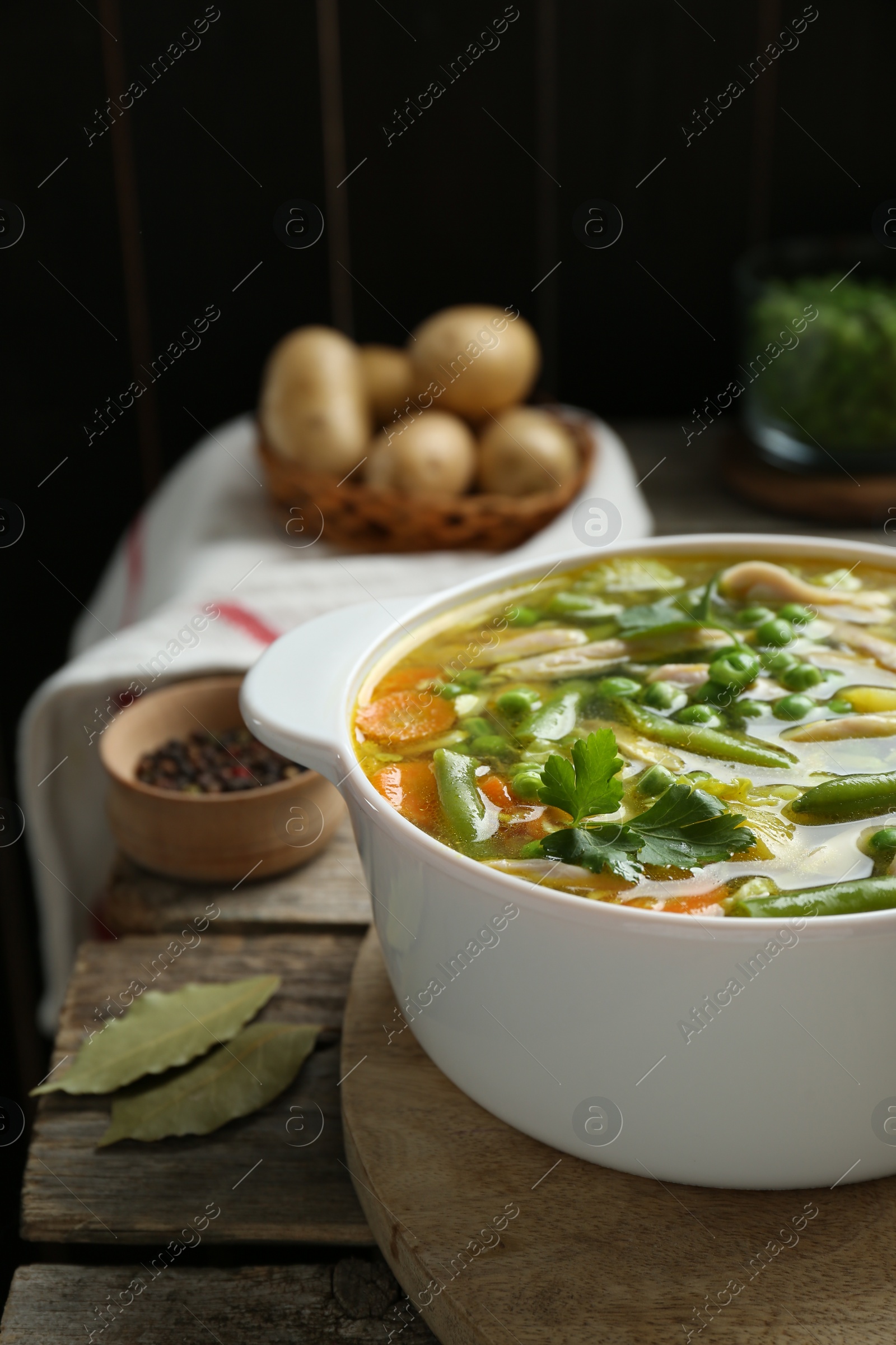 Photo of Saucepan of delicious vegetable soup with chicken on wooden table