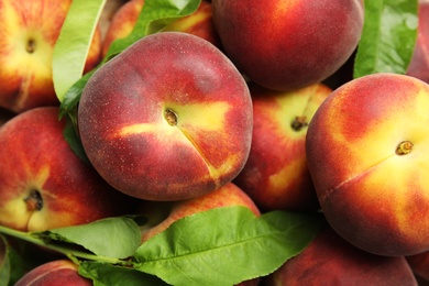 Photo of Tasty fresh peaches and leaves as background, top view