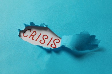 Photo of Word Crisis on white background, view through hole in torn light blue paper