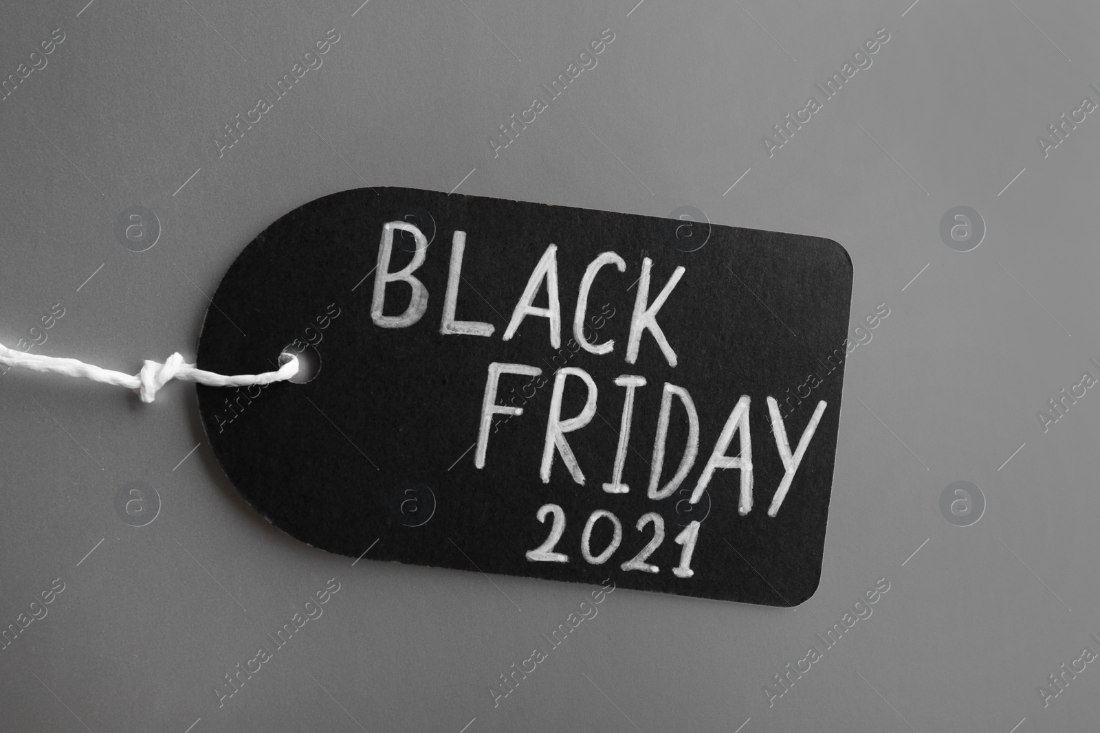 Photo of Tag with words BLACK FRIDAY 2021 on light grey background, top view