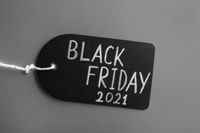 Photo of Tag with words BLACK FRIDAY 2021 on light grey background, top view