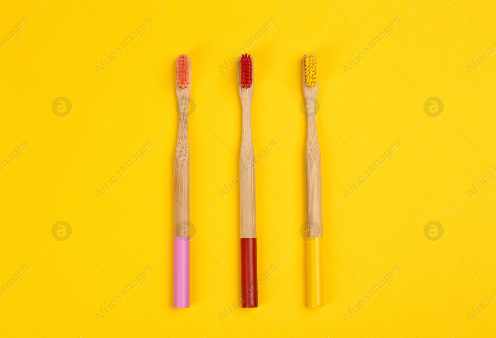 Photo of Toothbrushes made of bamboo on yellow background, flat lay. Space for text