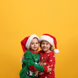 Photo of Kids in Christmas sweaters and Santa hats on yellow background