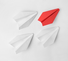 Photo of Idea concept. Grouppaper planes following red one on white background, flat lay