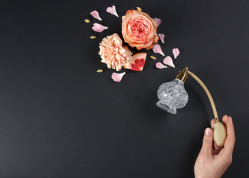 Photo of Woman with perfume. Fragrance composition, flowers and grapefruit on black background,  top view. Space for text