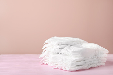 Photo of Baby diapers on wooden table against pink background. Space for text