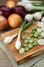 Photo of Different kinds of onions on wooden table, closeup