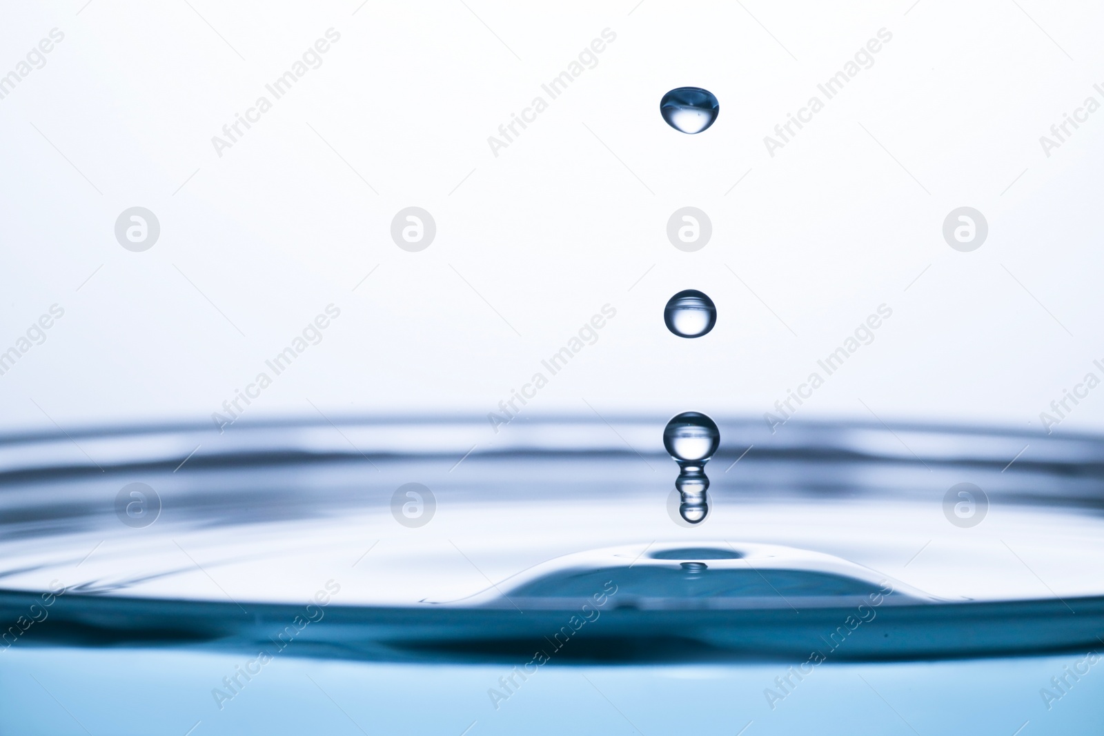 Photo of Splash of clear water with drops on light grey background, closeup