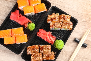 Tasty sushi rolls served on wooden table, top view. Food delivery