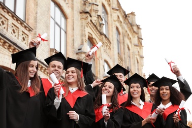 Photo of Happy students with diplomas outdoors. Graduation ceremony