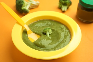 Photo of Healthy baby food and broccoli on orange background, closeup