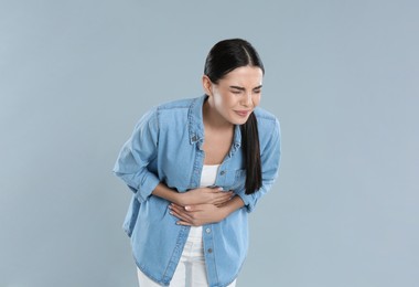Photo of Woman suffering from stomach ache on grey background. Food poisoning