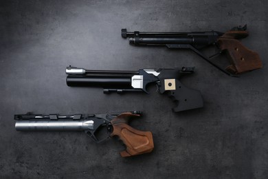 Photo of Many different sport pistols on black table, flat lay. Professional guns