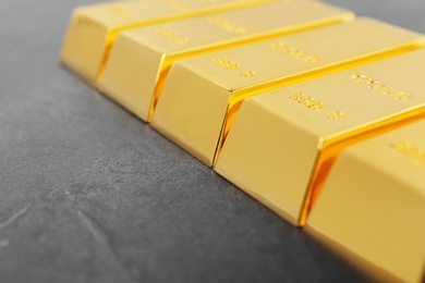 Photo of Gold bars on grey background, closeup. Space for text