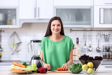 Young woman preparing tasty healthy smoothie at table in kitchen