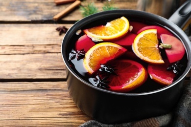 Delicious mulled wine on wooden table, closeup