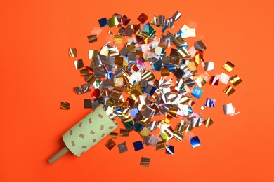 Photo of Party popper and colorful confetti on orange background, flat lay