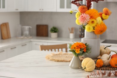 Photo of Beautiful autumn bouquets and pumpkins on marble table in kitchen