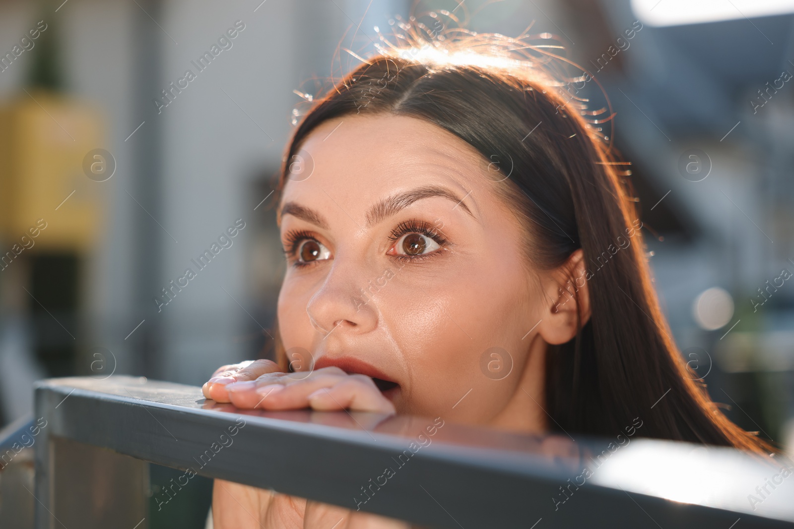 Photo of Concept of private life. Curious young woman spying on neighbours over fence outdoors, closeup