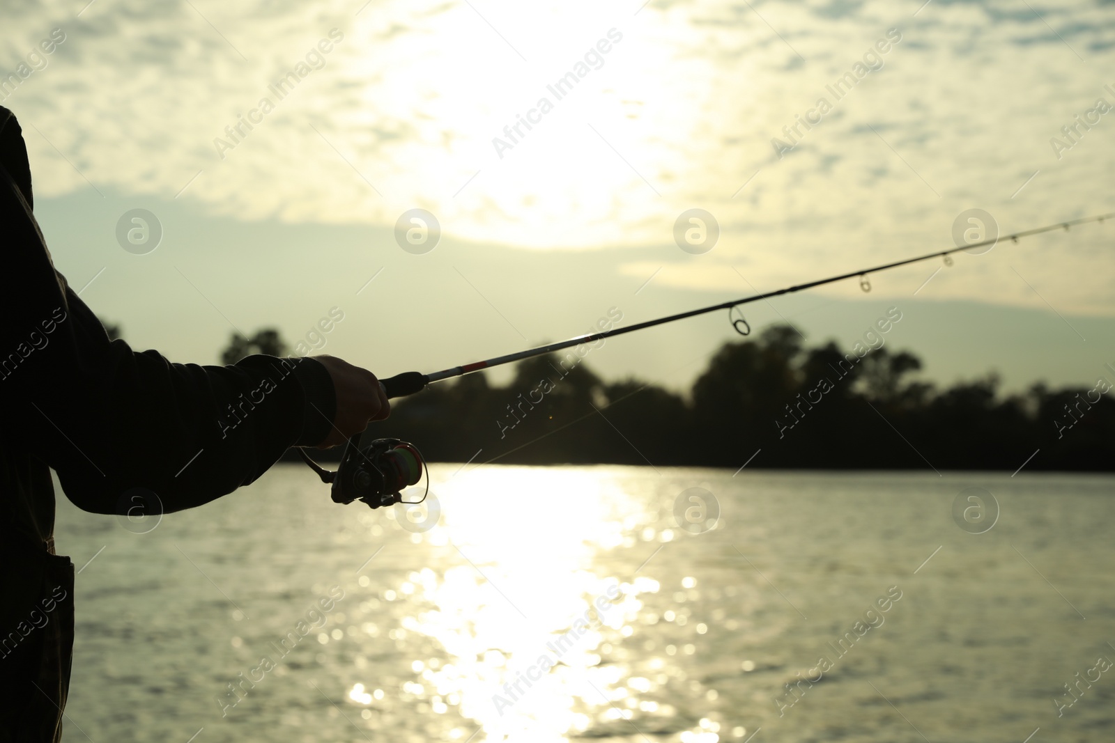 Photo of Fisherman with rod fishing at riverside, closeup