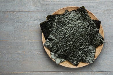 Photo of Dry nori sheets on grey wooden table, top view. Space for text