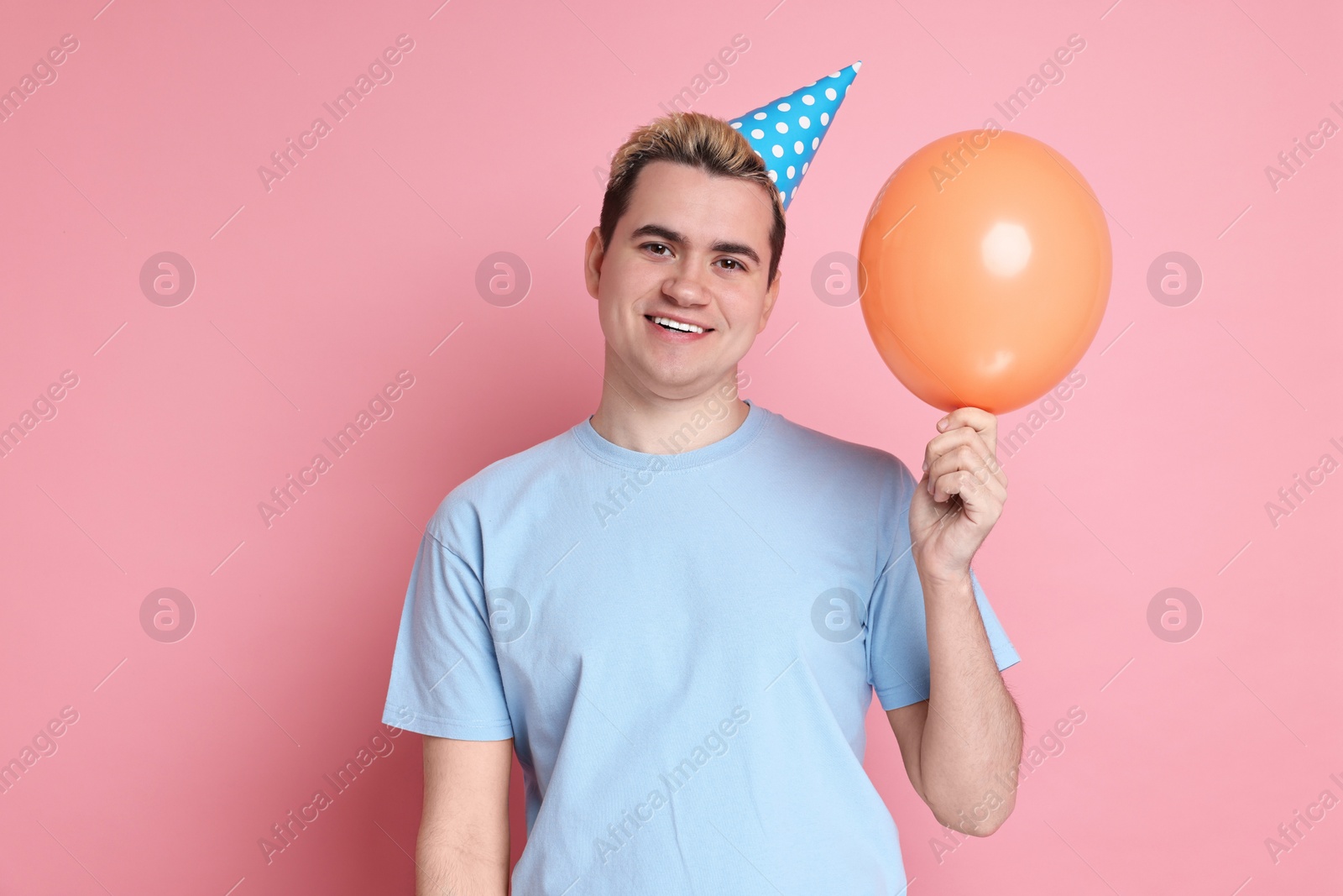 Photo of Young man with party hat and balloon on pink background