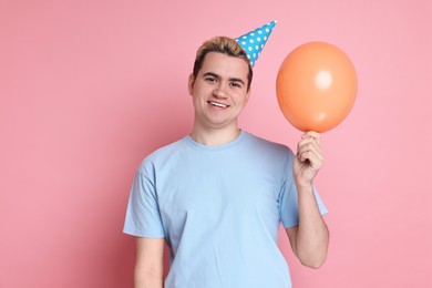 Photo of Young man with party hat and balloon on pink background