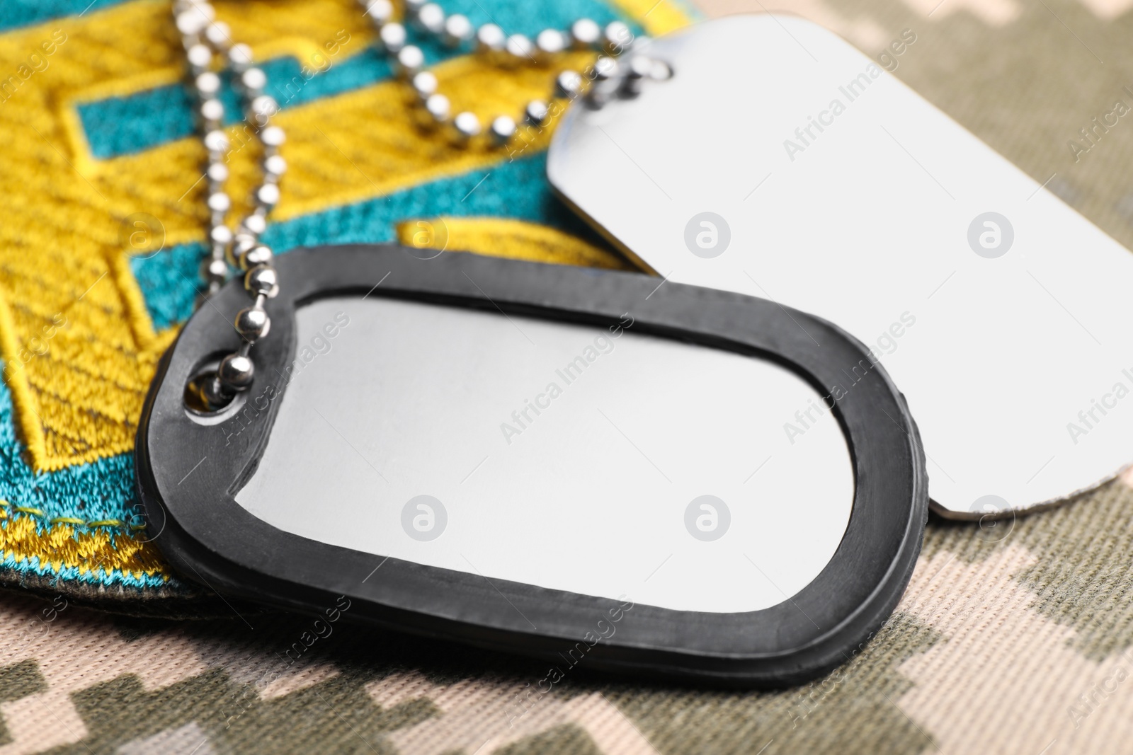 Photo of Military ID tags and Ukrainian patch on pixel camouflage, closeup