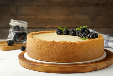 Photo of Delicious cheesecake decorated with blackberries on table