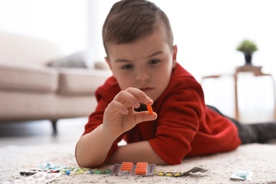 Little child with different pills on floor at home. Household danger