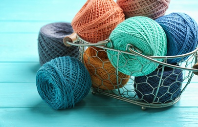 Photo of Colorful clews of threads in basket on table, closeup