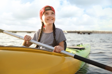 Happy little girl kayaking on river. Summer camp activity