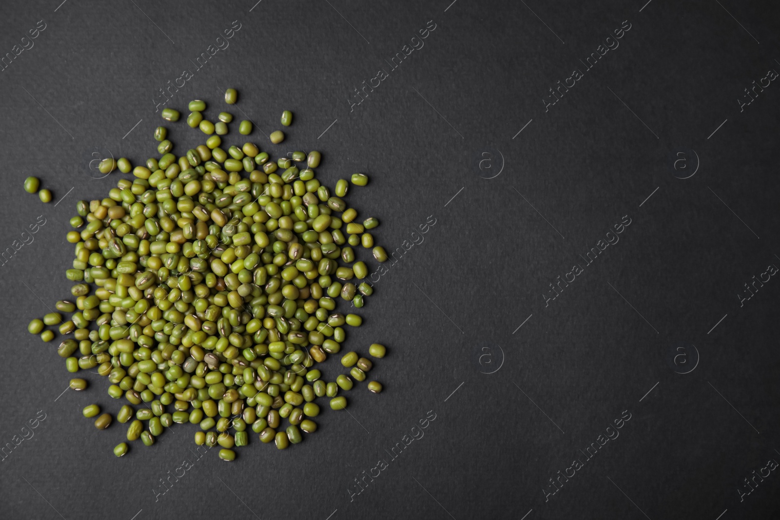 Photo of Pile of green mung beans on black background, top view. Space for text