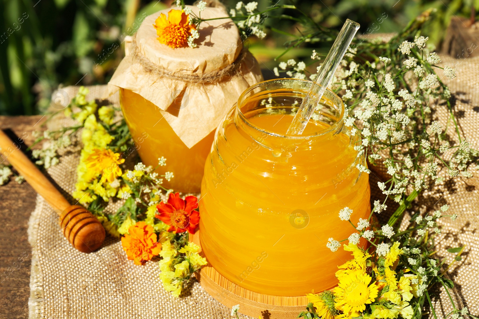 Photo of Delicious fresh honey and beautiful flowers on wooden table