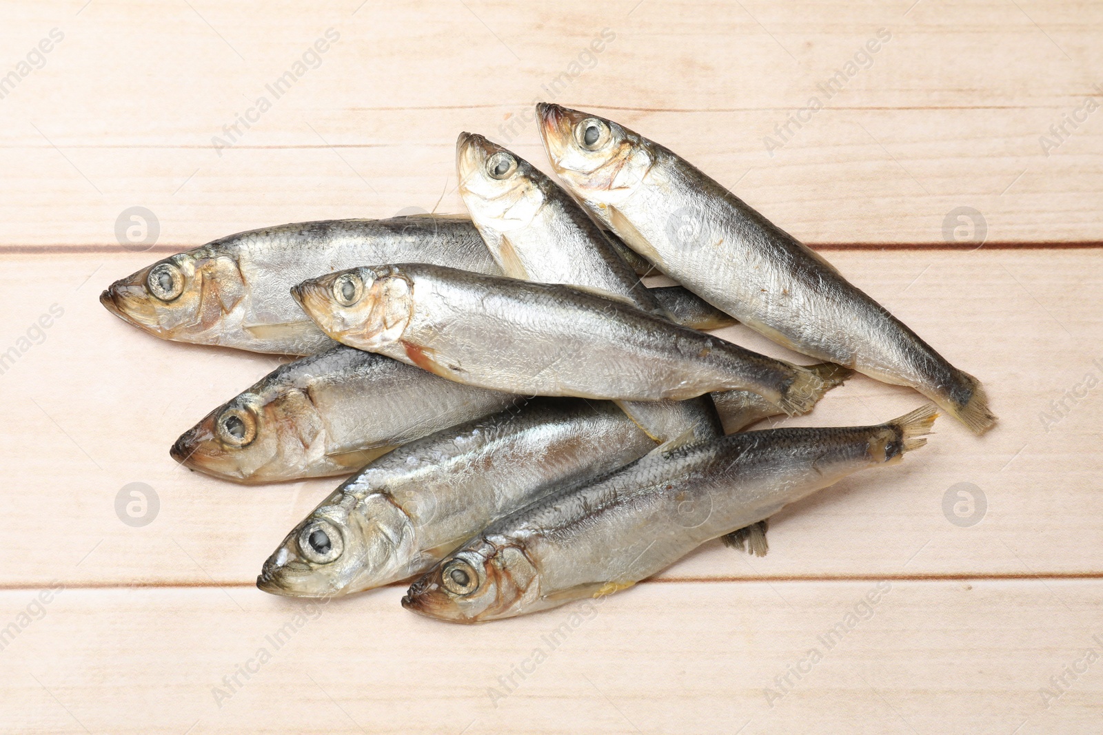 Photo of Fresh raw sprats on light wooden table, top view