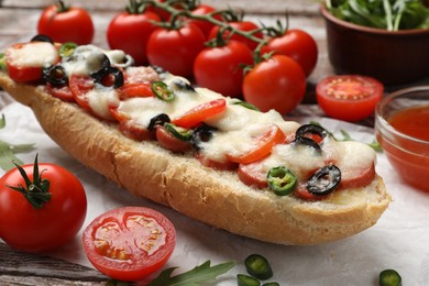 Photo of Tasty pizza toast and ingredients on wooden table, closeup
