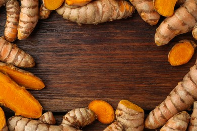 Frame made of many fresh turmeric roots on wooden table, flat lay. Space for text