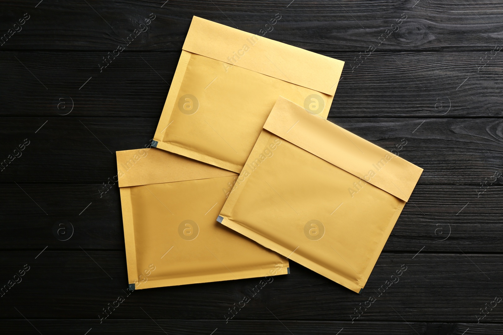 Photo of Kraft paper envelopes on black wooden background, flat lay