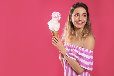 Portrait of young woman holding cotton candy dessert on pink background, space for text