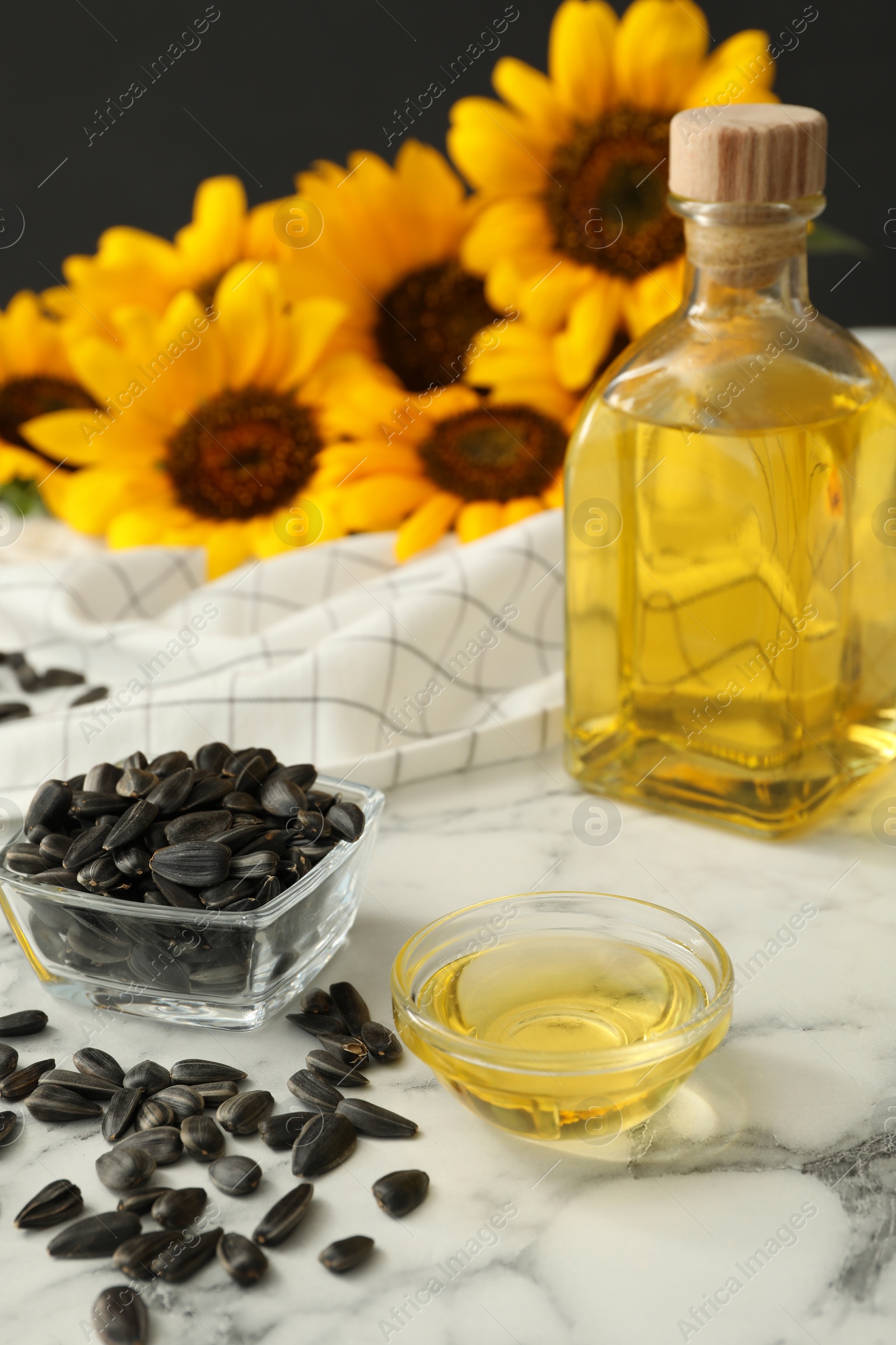 Photo of Sunflower oil and seeds on white marble table