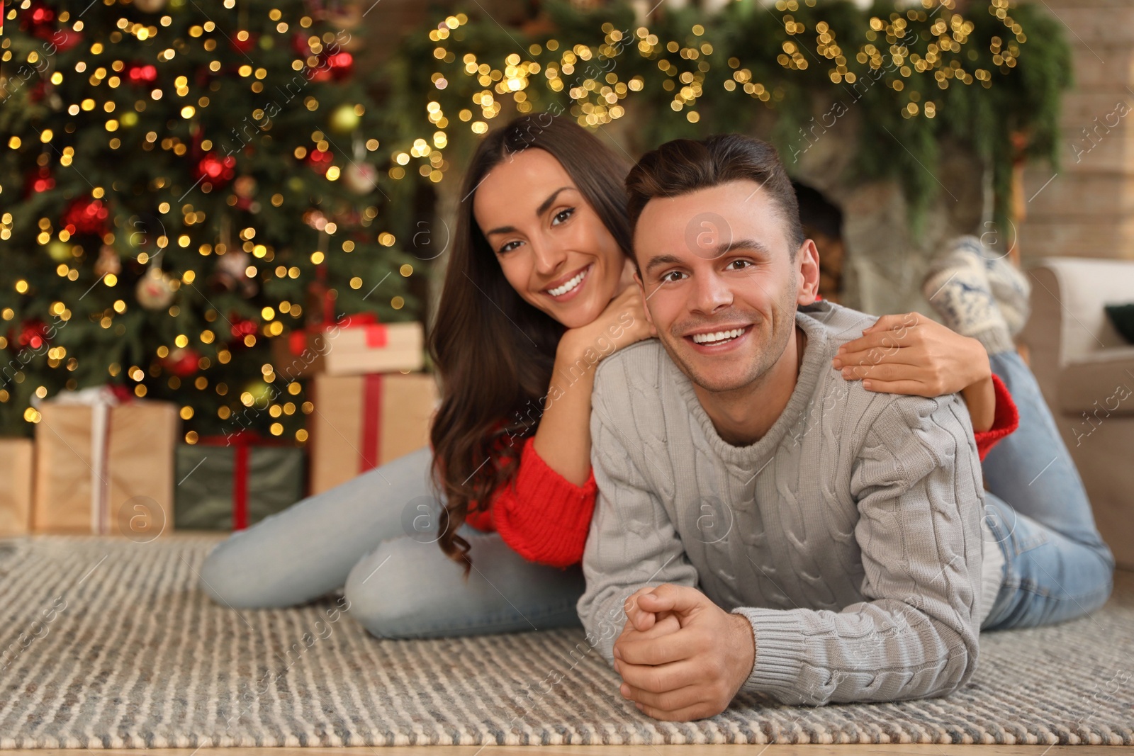 Photo of Happy young couple lying on floor in living room decorated for Christmas