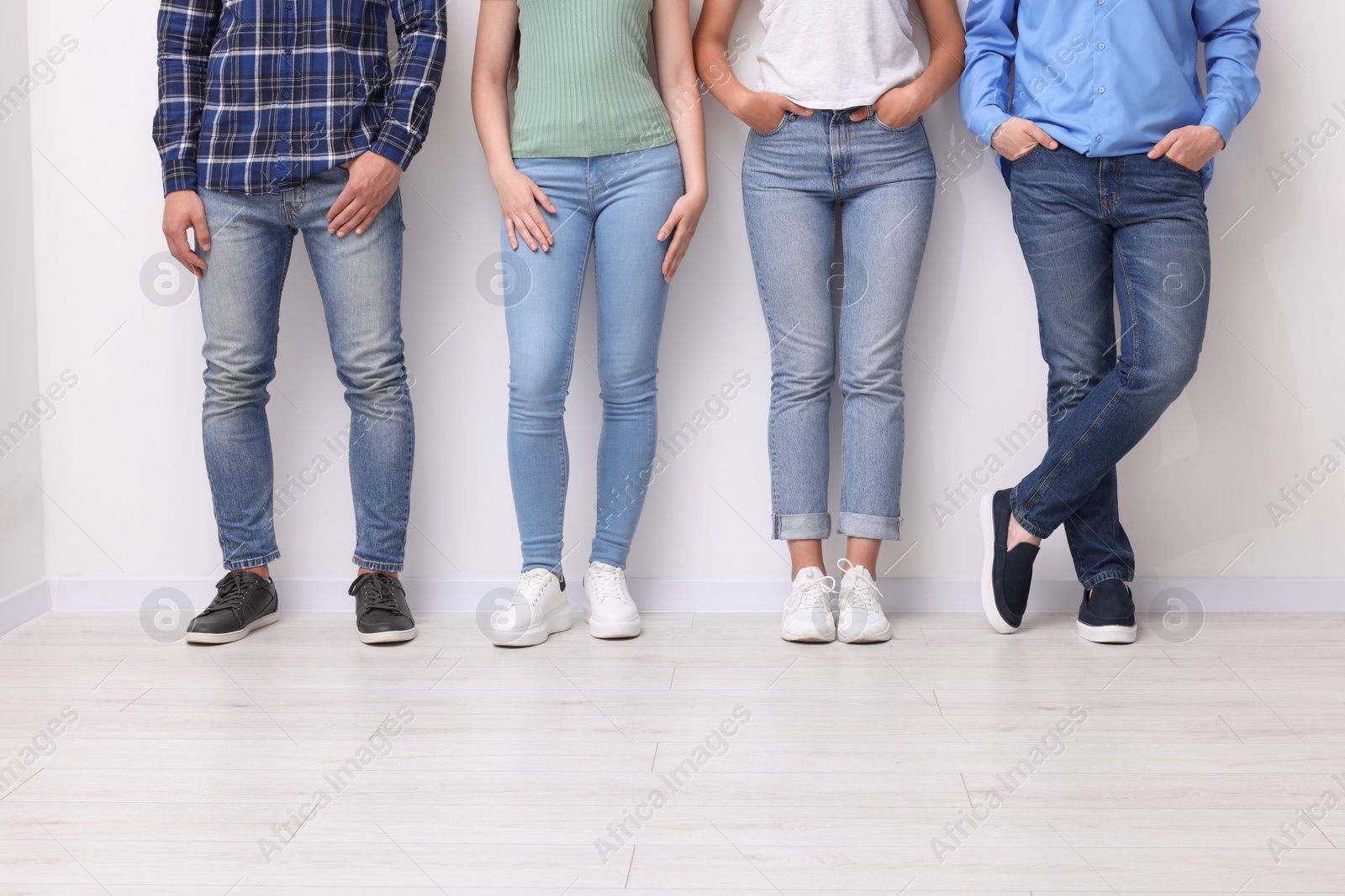 Photo of Group of people in stylish jeans near white wall indoors, closeup