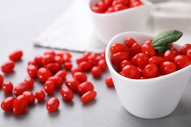 Photo of Bowl and fresh goji berries on grey background, closeup. Space for text