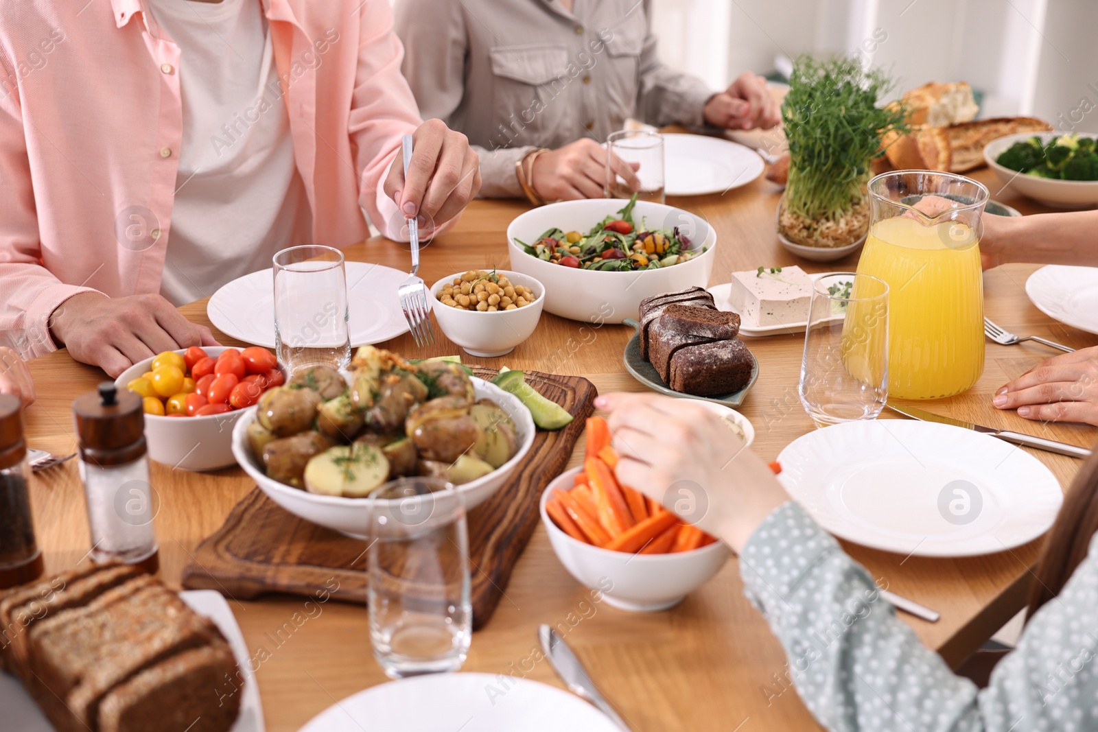 Photo of Friends eating vegetarian food at wooden table indoors, closeup