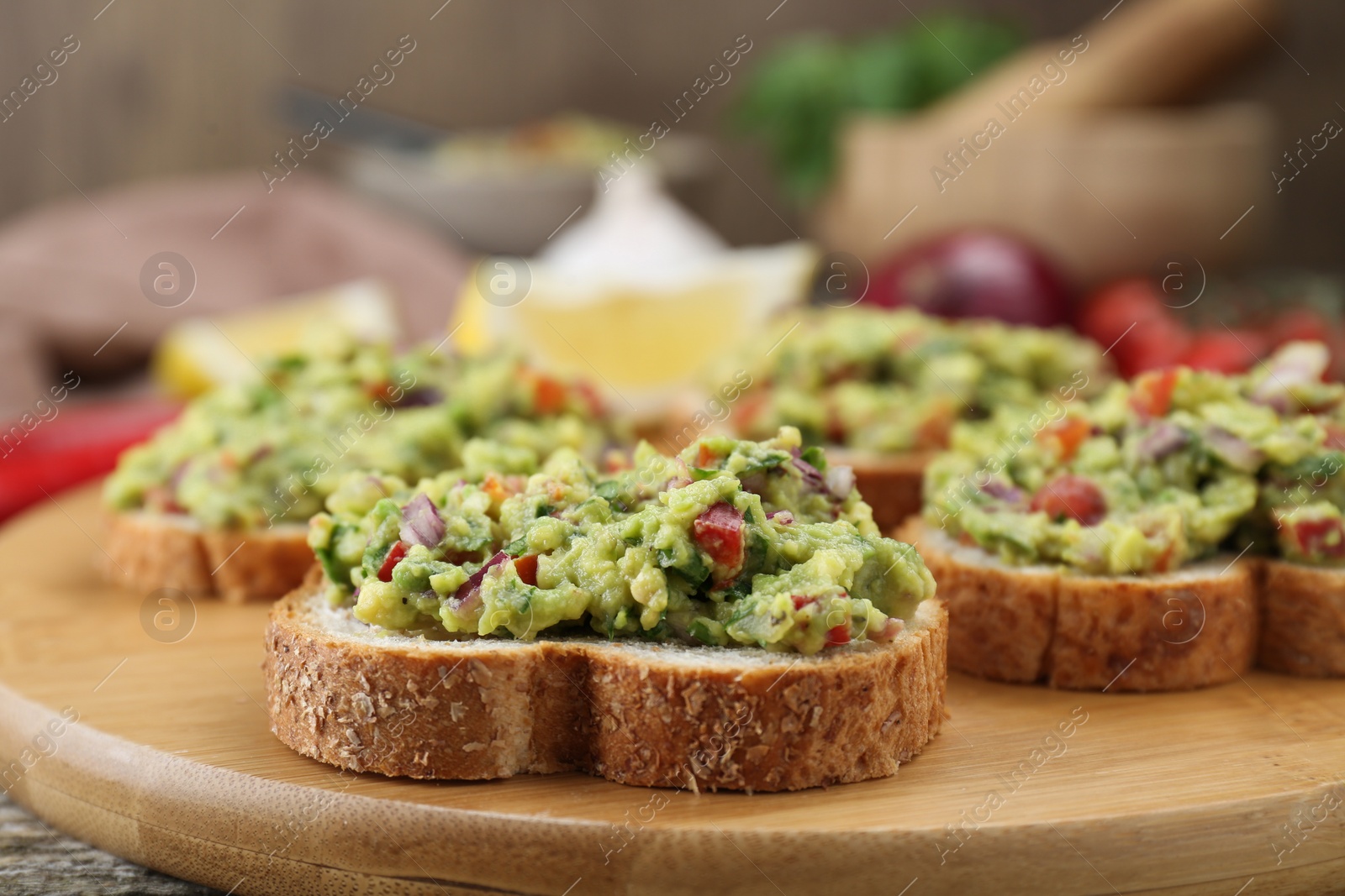 Photo of Slices of bread with tasty guacamole on wooden table, closeup